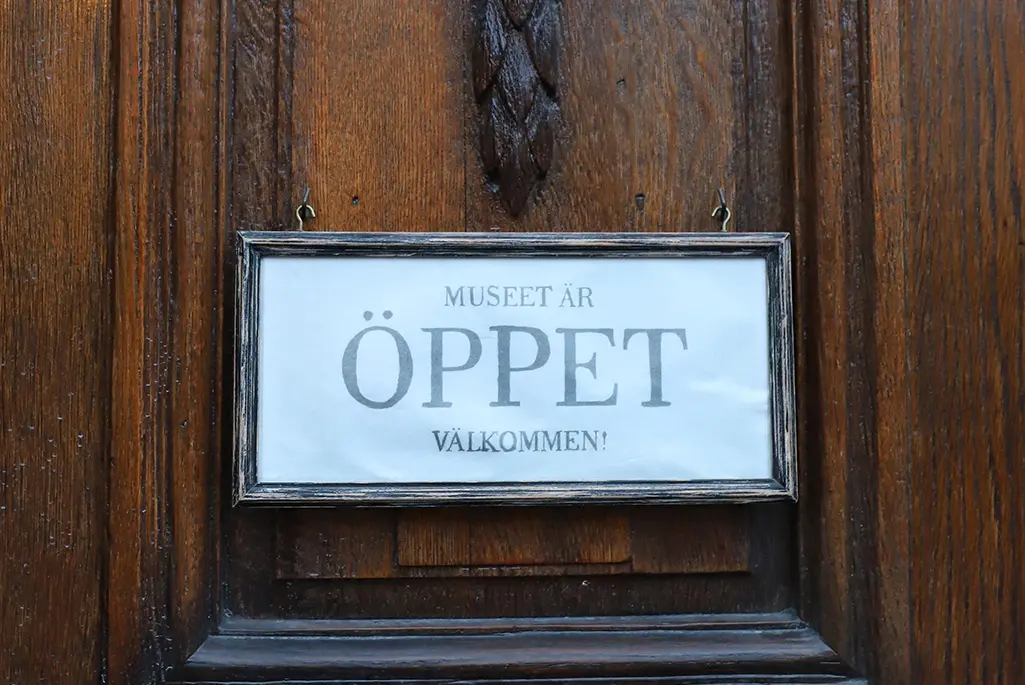 Mörk trädörr med skylt: Öppet