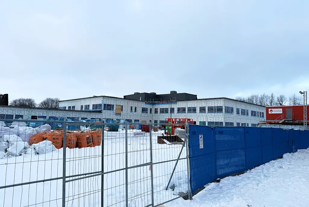 Inklädd byggnad i ett inhägnat byggområde.