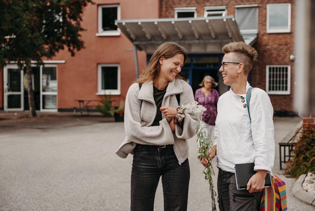 två skrattande kvinnor som har blommor i händerna.