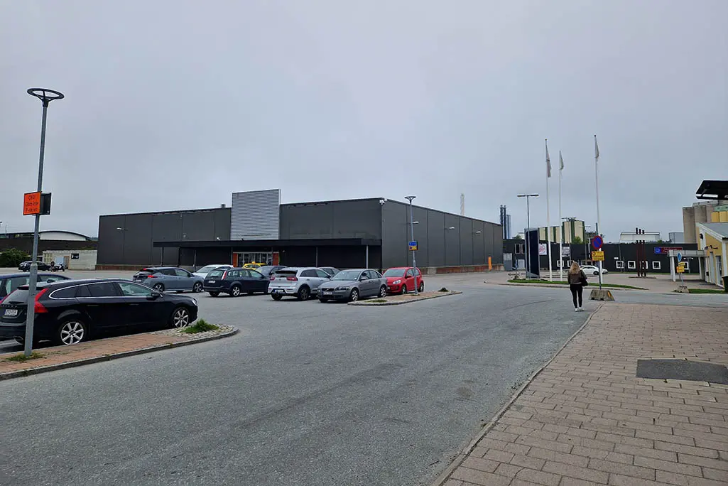 Bilden visar en parkeringsyta och en stor lokal med svart plåtfasad.