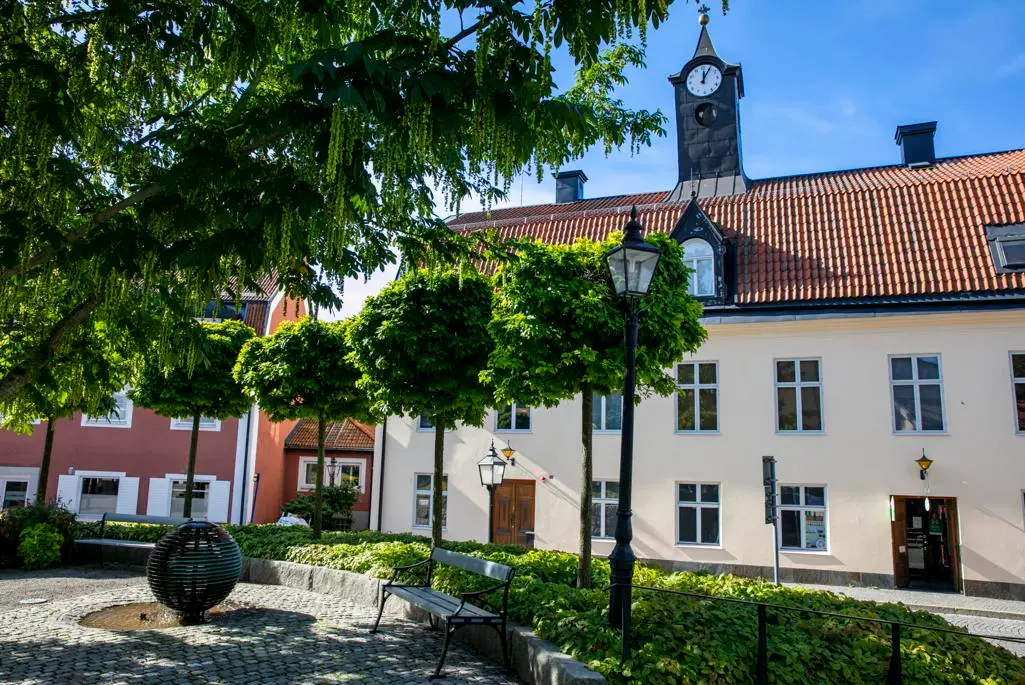 Beigefärgat hus med torn, gröna träd i förgrunden.