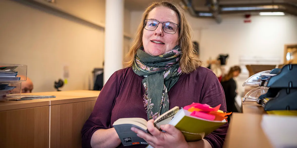 En kvinna håller i böcker i ler.