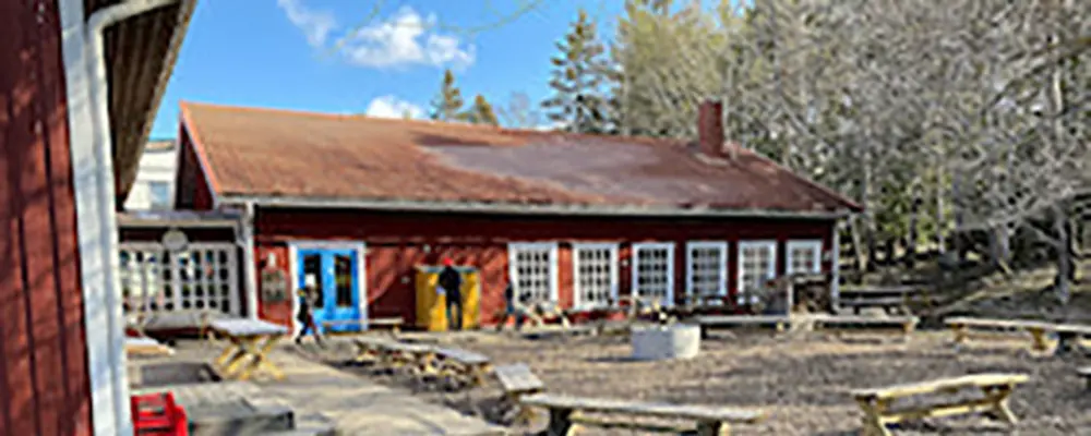 Foto av Robinson Husberg. Det är ett rött trähus med vita knutar och blåa dörrar. 