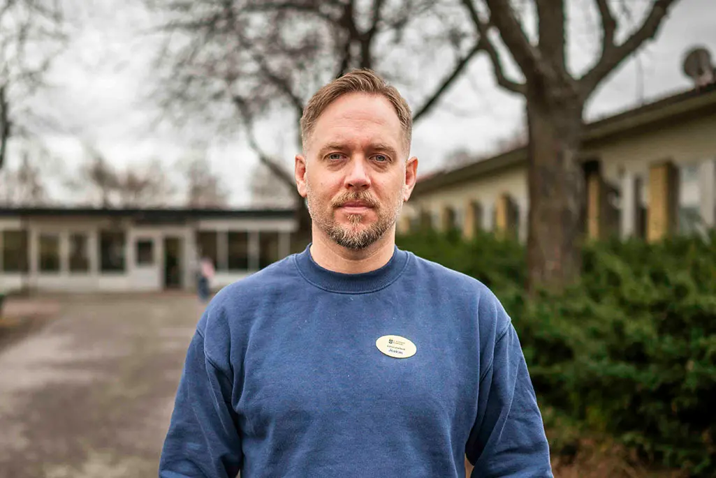 Man står framför en skolbyggnad, foto