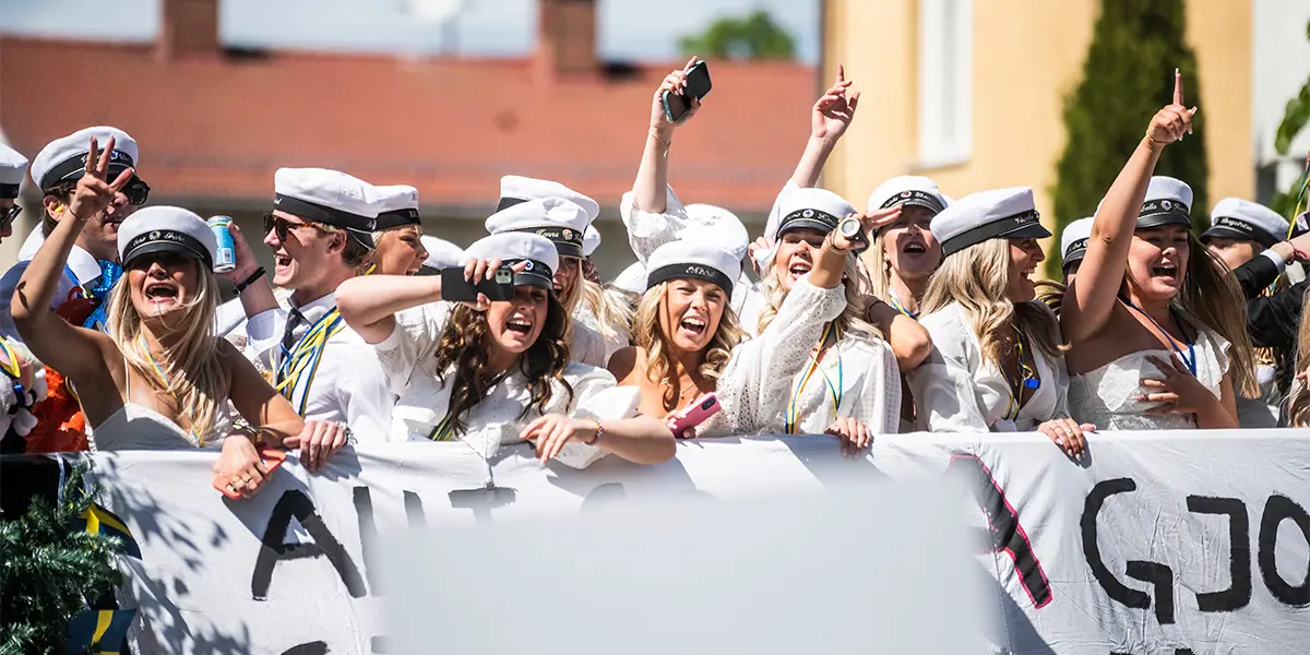 Studenter på ett flak, de ser glada ut och vinkar, foto